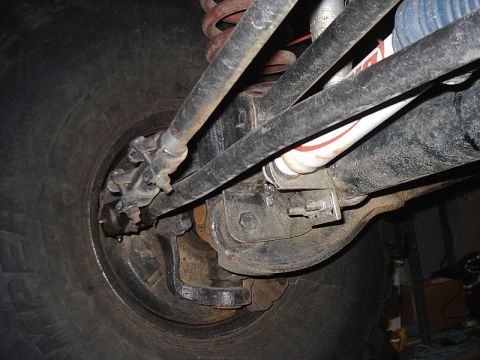 1996 Ford Bronco - Undercarriage view of a vehicle's suspension system, focusing on the steering components and tire.