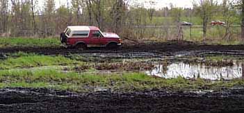 1989 Ford Bronco - 1989 Ford Bronco navigating a challenging muddy terrain.