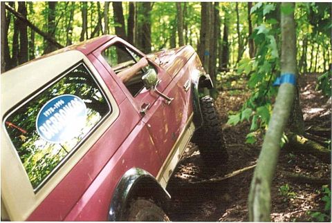 1989 Ford Bronco - This 1989 Ford Bronco is navigating a challenging off-road trail in a forest.
