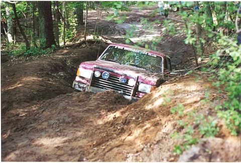 1989 Ford Bronco - This vehicle is deeply embedded in a muddy rut, suggesting a challenging off-road situation.