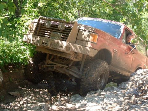 1989 Ford Bronco - This modified SUV is tackling a challenging off-road course with large tires and a lifted suspension.