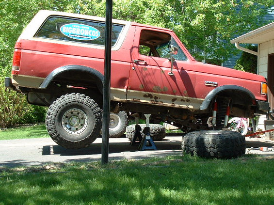1989 Ford Bronco on jack stands with front wheel removed, undergoing maintenance