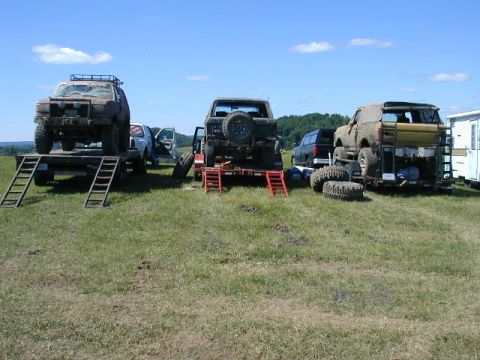 1989 Ford Bronco - Multiple off-road vehicles are staged on trailers in a field.