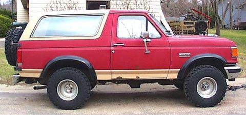 1989 Ford Bronco - This red Ford Bronco features tan two-tone trim and a spare tire mounted on the rear tailgate.