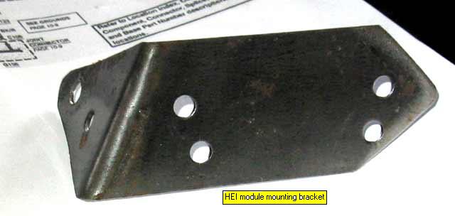Dark steel L-shaped bracket with drilled holes on printed paper