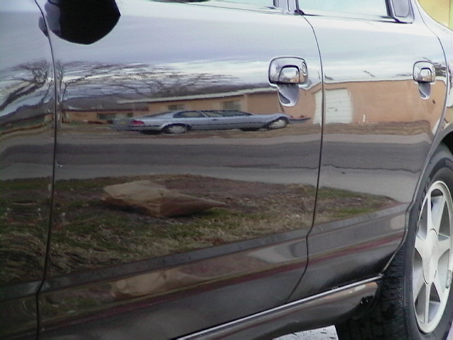 Reflection of a silver sedan with a distinctive body style, seen from the side