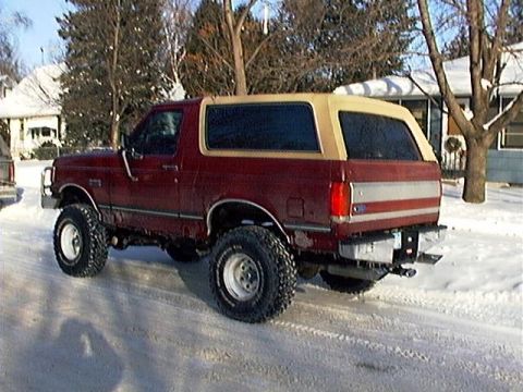 1991 Ford Bronco - This Ford Bronco is parked on a snow-covered road with houses in the background.