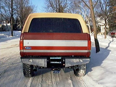 1991 Ford Bronco - A 1991 Ford Bronco is parked on a snowy road, showing its rear end with a two-tone paint scheme.