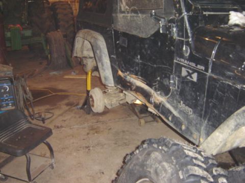 1992 Ford Bronco - A black Jeep Wrangler is shown with its front wheel removed and supported by jack stands in a garage setting.