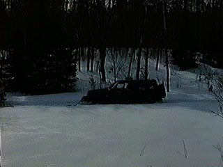 1991 Ford Bronco - A dark-colored SUV is seen parked in a snow-covered landscape with trees in the background.