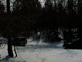 1991 Ford Bronco - Two SUVs are parked in a snowy, wooded area, with trees obscuring much of the view.