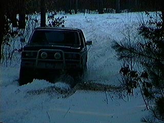 1991 Ford Bronco - 1991 Ford Bronco navigating a snow-covered path in a wooded area.