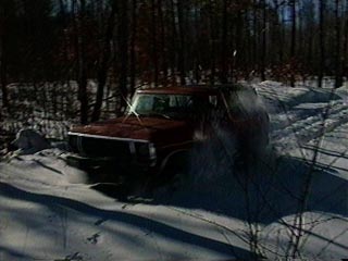 1991 Ford Bronco - A red 1978 Ford Bronco navigates a snowy path in a wooded area.