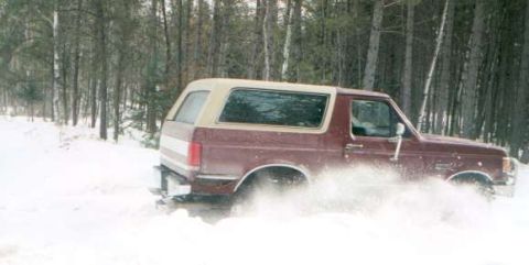 1991 Ford Bronco - Maroon 1991 Ford Bronco kicking up snow while driving on a wooded path.