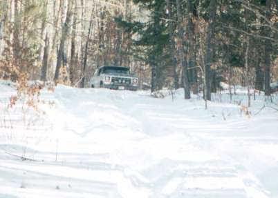 1991 Ford Bronco - 1991 Ford Bronco navigates a snowy path through a forest.