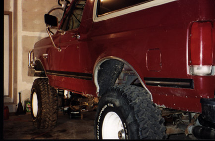 1991 Ford Bronco - This lifted 1991 Ford Bronco has large off-road tires and appears to be in a garage or workshop.