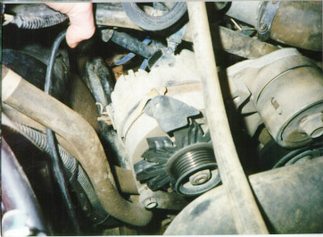 1991 Ford Bronco - Close-up view of an alternator and surrounding engine parts within a vehicle.