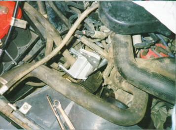 1991 Ford Bronco - Engine bay detail showing various hoses and electrical connections, with a red distributor cap visible.