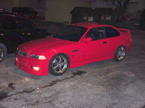 1995 BMW M3 - A red 1995 BMW M3 coupe is parked next to a black SUV at night.
