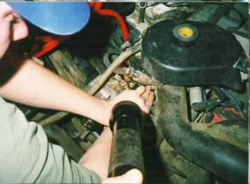 1991 Ford Bronco - A person inspects a component within the engine bay, illuminated by a flashlight.
