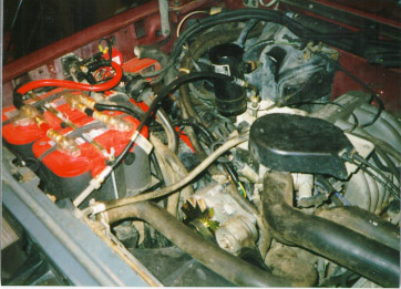 1991 Ford Bronco - Close-up view of an engine bay dual batteries and various engine parts.