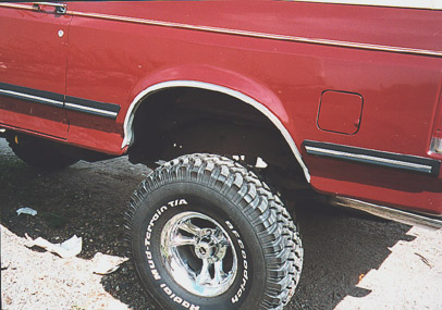 1991 Ford Bronco - A red truck with a lifted suspension and BFGoodrich Mud-Terrain T/A tires is shown from the side.
