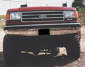 1991 Ford Bronco - This red Ford Bronco features large tires and 4x4 badging, seen from a front-facing perspective.