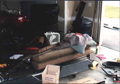 1991 Ford Bronco - A cluttered garage scene with a couch and a red vehicle partially visible.
