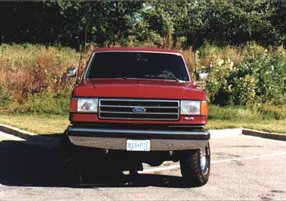 1991 Ford Bronco - Red Ford F-Series truck parked outdoors, showing its front grille and headlights.