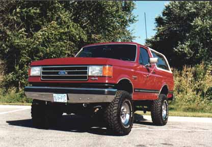 1991 Ford Bronco - This red Ford Bronco is shown from the front-three-quarter view, parked outdoors.
