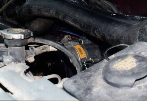 1991 Ford Bronco - A close-up view of engine components, including hoses and a yellow label on a part.