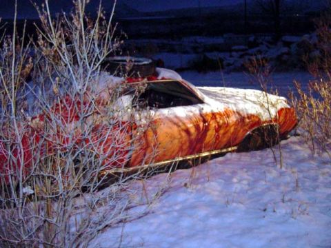 1969 Mercury Cougar - A red car sits abandoned in the snow, partially obscured by branches, with a Supermotors watermark visible in the lower right corner.