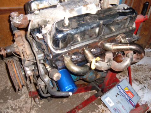 1985 Ford F-150 - A Ford V8 engine is mounted on a red engine stand, showing its various components and exhaust system.