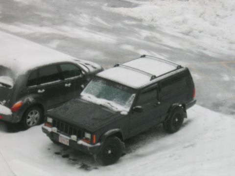 2000 Jeep Liberty - A black Jeep Cherokee XJ sits covered in snow next to another vehicle.