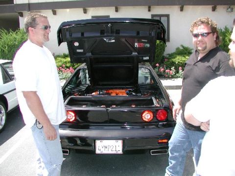 1986 Pontiac Fiero - Rear view of a black 1986 Pontiac Fiero with its trunk open, revealing the engine.
