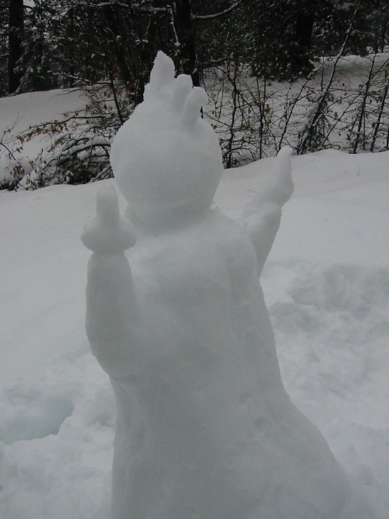 Snow sculpture with raised arms in a snowy outdoor setting