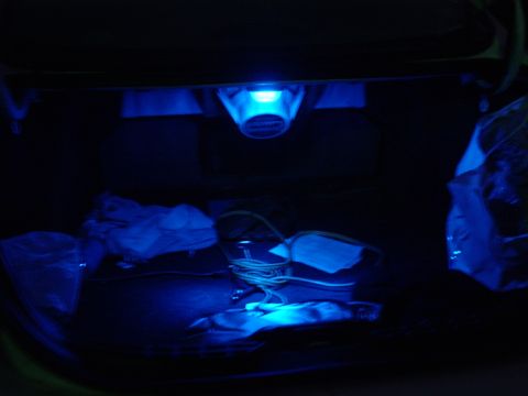 2000 Ford Taurus - The interior of a car trunk is illuminated by blue lights, with various items scattered inside.