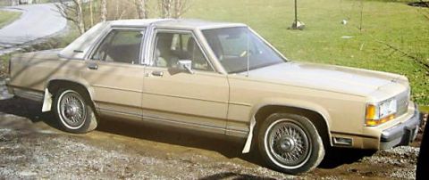 1989 Ford Crown Victoria LTD - Tan 1989 Ford Crown Victoria LTD sedan with wire wheels parked on a gravel driveway.