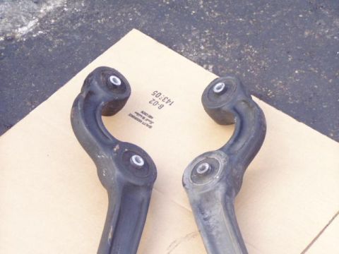1996 Ford Bronco - Two automotive control arms are shown, resting on a piece of cardboard.
