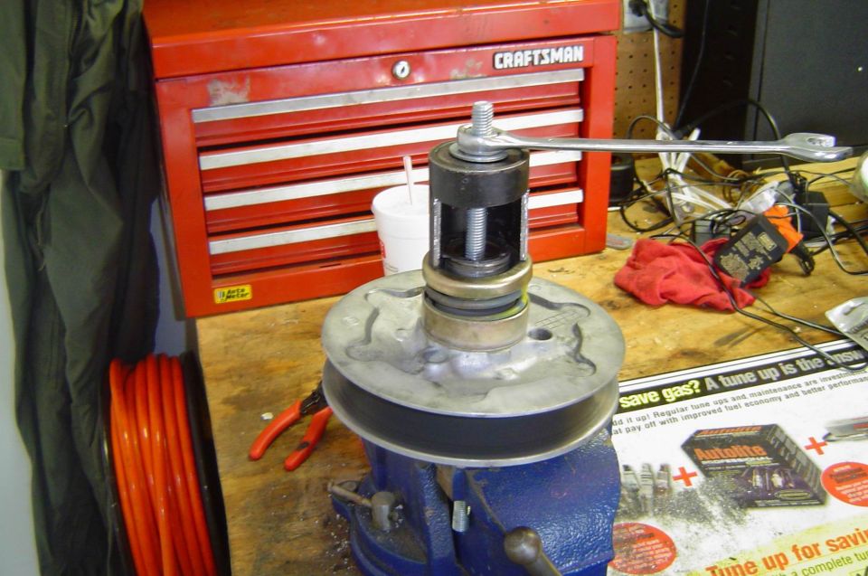 Pulley hub in a blue bench vise with a puller tool and wrench, red Craftsman toolbox behind