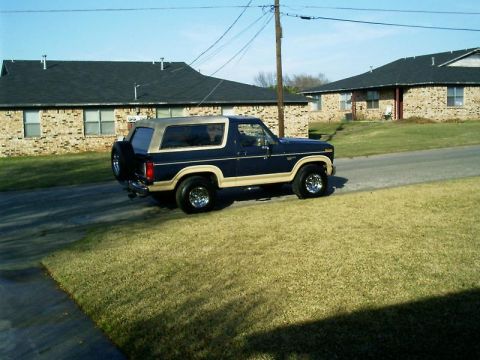 1986 Ford Bronco - This Ford Bronco is parked on a residential street with two houses in the background.