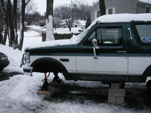 1994 Ford Bronco - 1994 Ford Bronco on jack stands in the snow, undergoing maintenance.