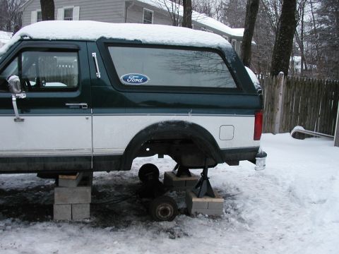 1994 Ford Bronco - This 1994 Ford Bronco is elevated on blocks and jack stands with its rear axle removed, sitting in a snowy yard.