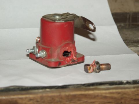 1979 Ford Bronco - A damaged starter solenoid and a detached bolt are shown on a white surface.