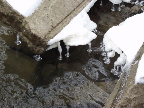 1979 Ford Bronco - Icicles drip from snow-covered concrete into dark, rippling water below.