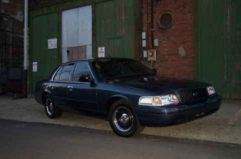 1998 Ford Crown Victoria - A dark blue 1998 Ford Crown Victoria is parked in an urban alleyway.