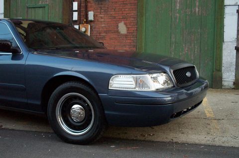1998 Ford Crown Victoria - Dark blue 1998 Ford Crown Victoria parked in front of a brick wall and green doors.