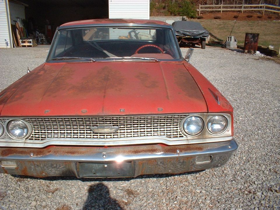 Red 1963 Ford Galaxie with a rusty chrome bumper and grille, seen from the front