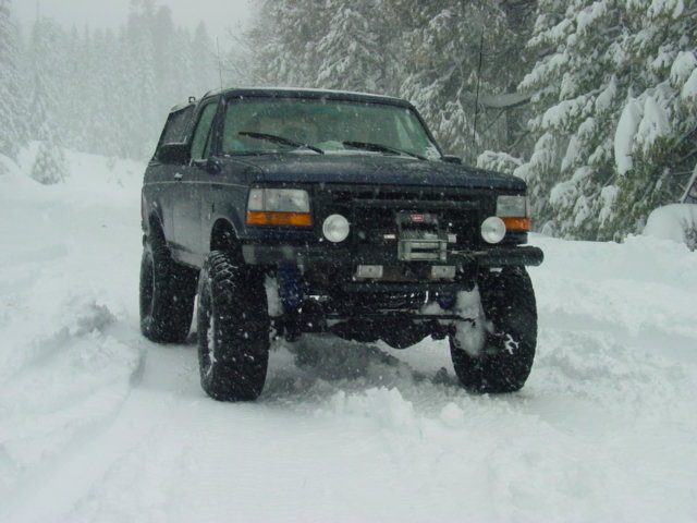 Dark blue Ford Bronco with lifted suspension and winch in deep snow, front view