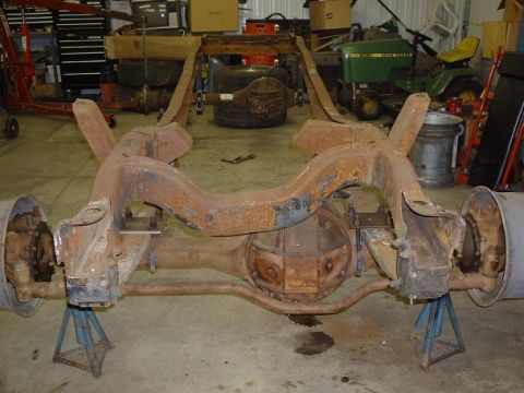 1978 Ford F-350 - The heavily rusted frame and rear axle assembly of a truck are supported by jack stands in a workshop setting that appears to be a workshop.
